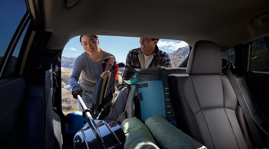 View from inside the cargo trunk of a 2026 Subaru Crosstrek as a man and woman pack backpacks, paddles, and coolers