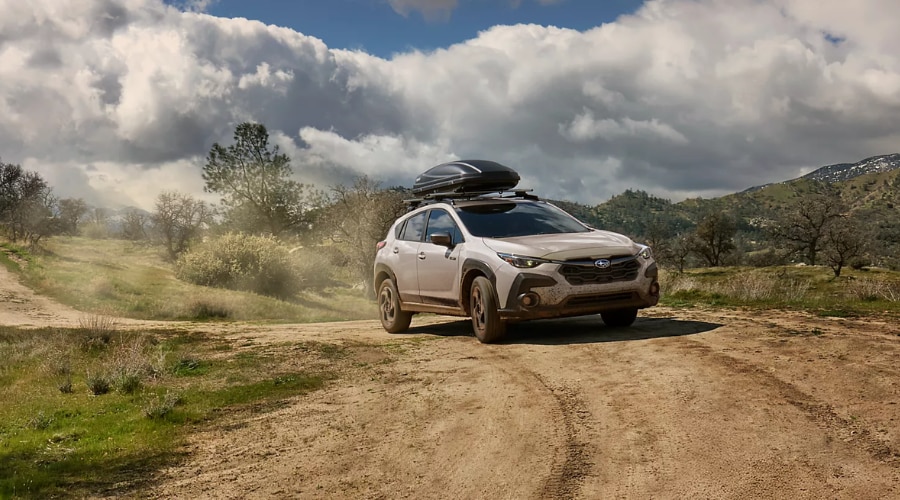 2026 Subaru Crosstrek equipped with a roof cargo carrier navigating dusty gravel paths in Dual-Function X-MODE during a weekend camping trip near Ramsey, NJ.