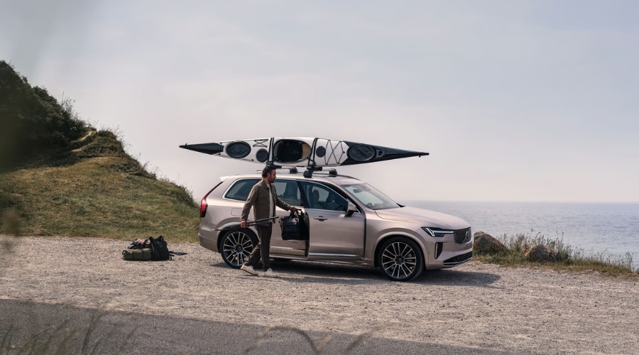 Passenger-side profile of the 2026 Volvo XC90 B6 Mild Hybrid with a kayak mounted on the roof rack, showcasing the outstanding outdoor utility and luxury hybrid crossover cargo space for families in Mahwah and Saddle River, NJ