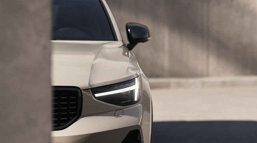 Close-up front angle of a beige 2026 Volvo XC40 luxury SUV showcasing the sleek headlight design, gloss black side mirror, and premium front bumper lines in Ramsey.