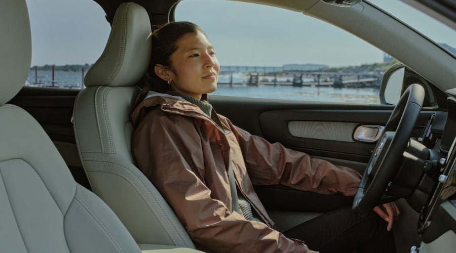 Woman sitting comfortably in the driver seat of a 2026 Volvo XC40 with light leather interior, showcasing Scandinavian cabin comfort and clean air relaxation during autumn commutes in Ramsey, NJ.