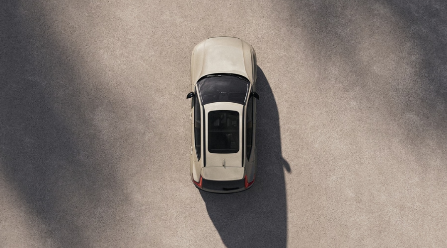 An aerial top down view of a Sand Dune beige 2026 Volvo XC40 showing the black panoramic glass sunroof and clean design lines from above.