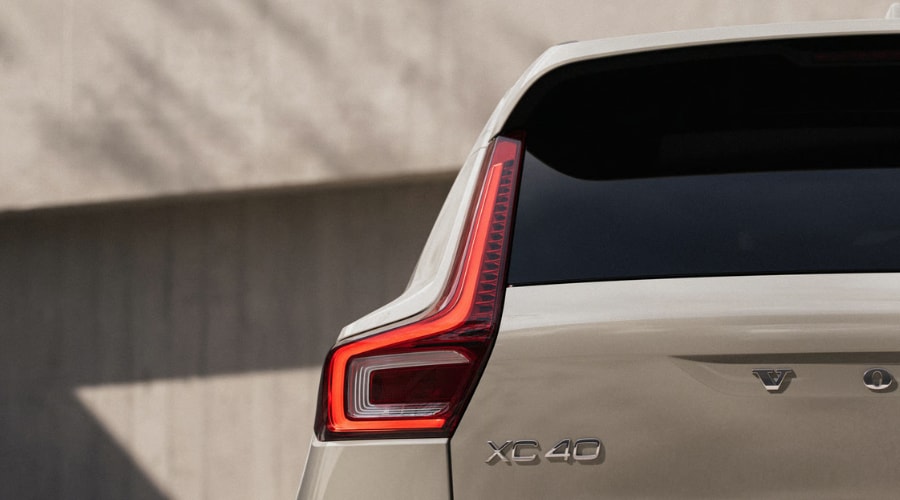 Close-up rear view of a cream 2026 Volvo XC40 SUV highlighting the vertical LED taillight and chrome XC40 badging, representing Rear Auto Brake and radar safety tech for Ramsey, NJ drivers.