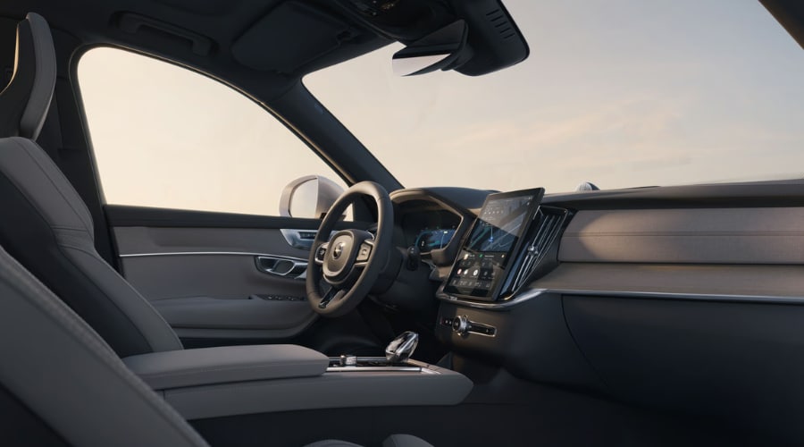 Passenger-side interior view of the 2026 Volvo XC90 front cockpit showcasing the vertical center touchscreen display, Scandinavian dashboard trim, leather driver seat, and steering wheel tech for local drivers in Ramsey, NJ.