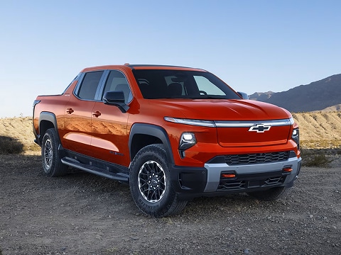 orange 2025 Chevrolet Silverado electric truck on a road in plano, TX
