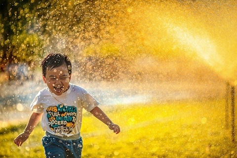child running through a sprinkler in plano, tx