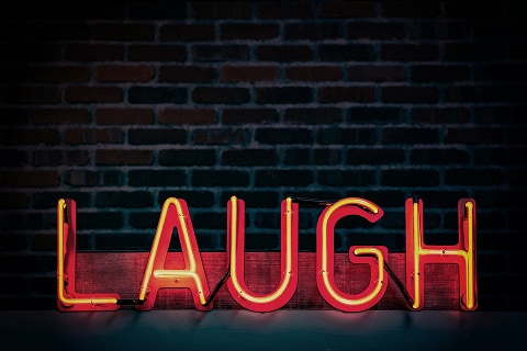 a lit neon sign that says laughter