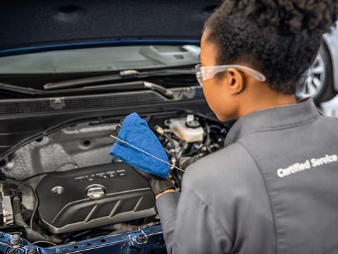 a chevrolet technician checking the oil on a dipstick