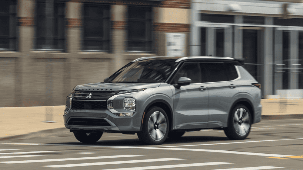 2025 Mitsubishi Outlander SUV in gray driving through Reading, PA city streets showcasing new design updates