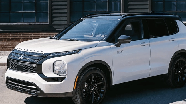 2025 Mitsubishi Outlander PHEV in white parked on city street near Reading, PA showcasing fuel-efficient hybrid performance