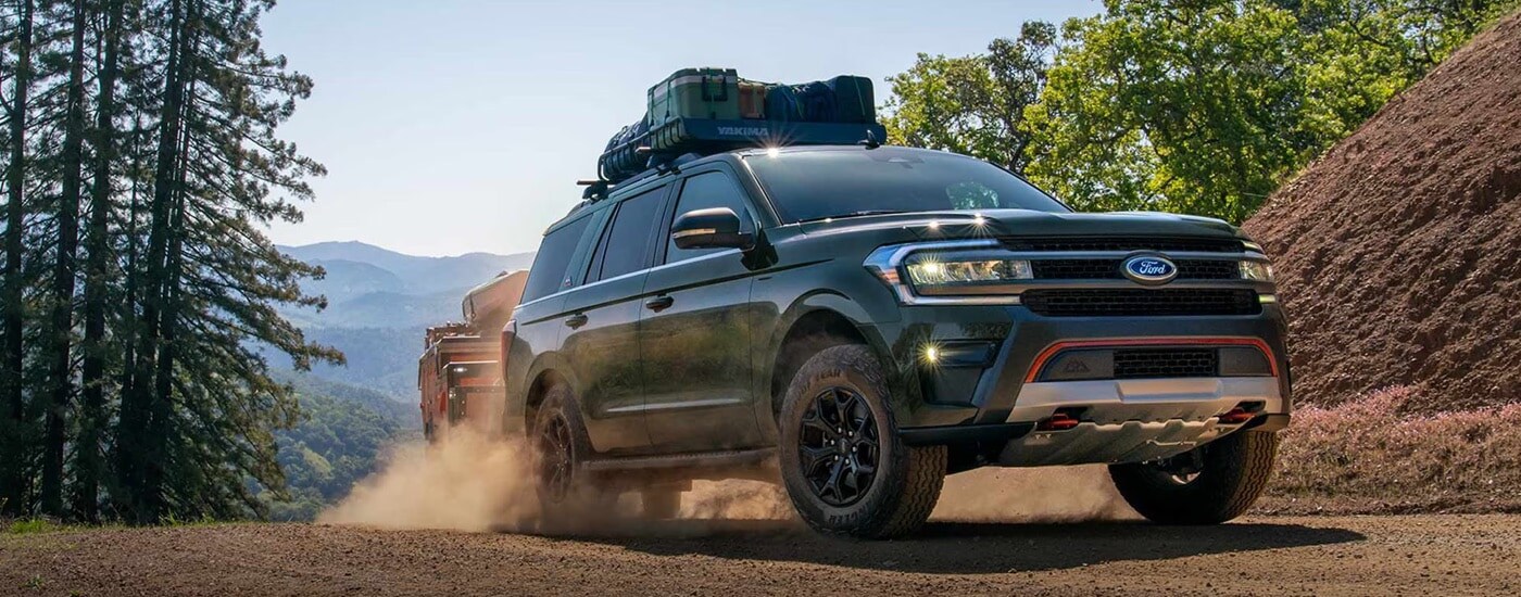 A green 2024 Ford Expedition Timberline driving on a dusty trail to a Ford dealer near Carey.