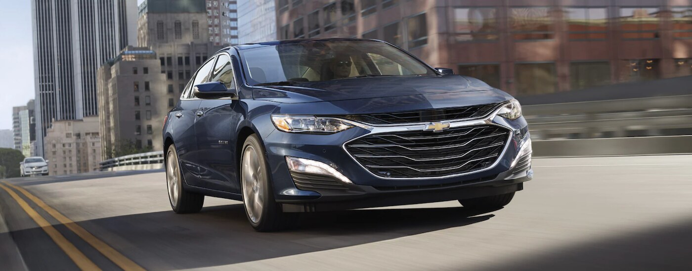 Blue 2022 Chevy Malibu driving through a city.