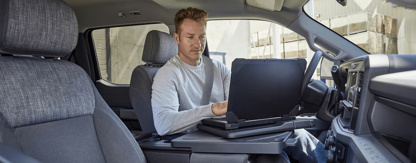 A man is using a laptop in a 2025 Ford F-250 STX.