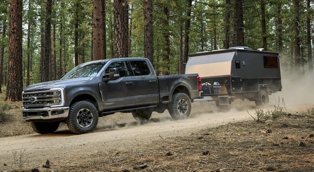 A grey 2025 Ford F-250 Lariat Tremor is shown towing a pop-up camper.