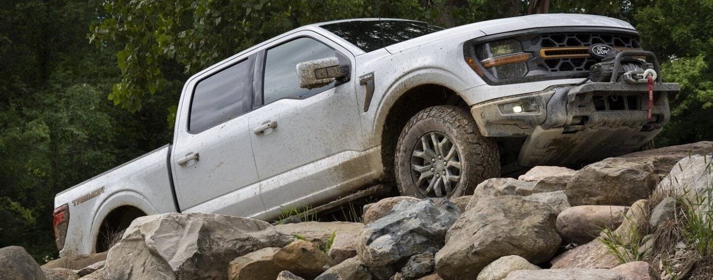 A white 2025 Ford F-150 Tremor is shown from the side off-road.