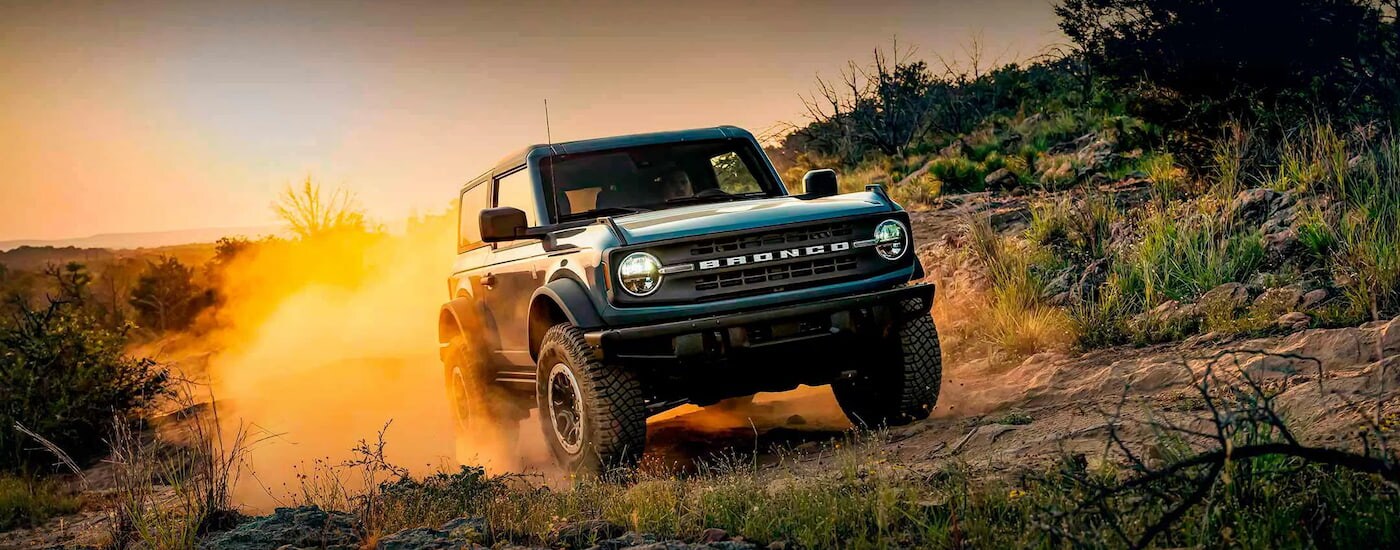 A blue 2024 Ford Bronco Black Diamond off-roading on a dusty trail.