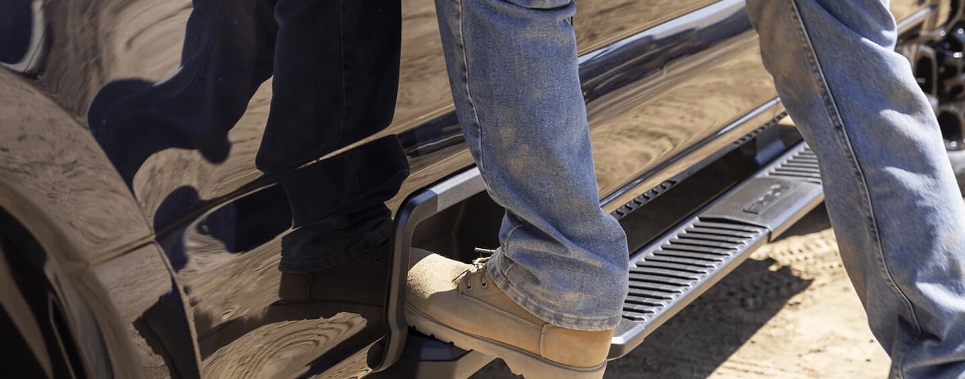 A person is stepping on the side step of a black 2025 Ford F-250 XL.