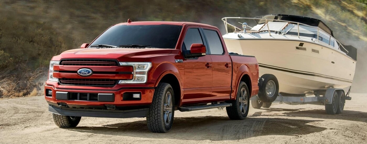 A red 2019 Ford F-150 STX is shown towing a boat.