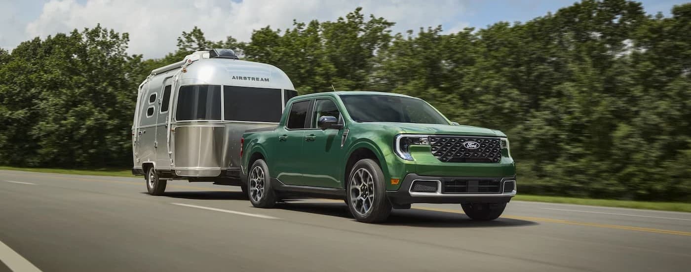 A green 2025  Ford Maverick towing a trailer.
