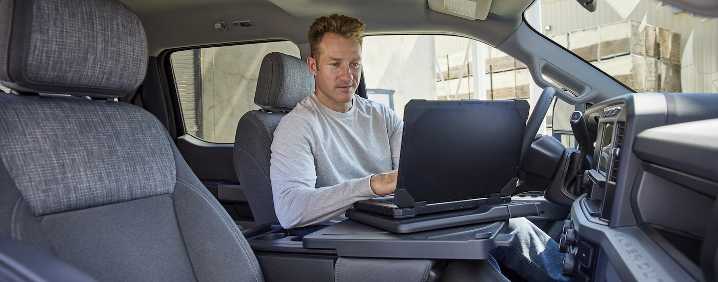 A man working on his laptop in the cabin of a 2024 Ford F-250 for sale in Findlay.