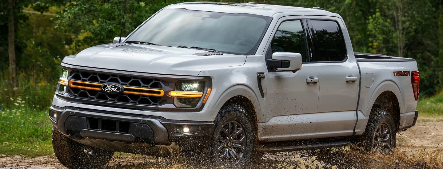 A silver 2025 Ford F-150 Tremor off-roading in mud