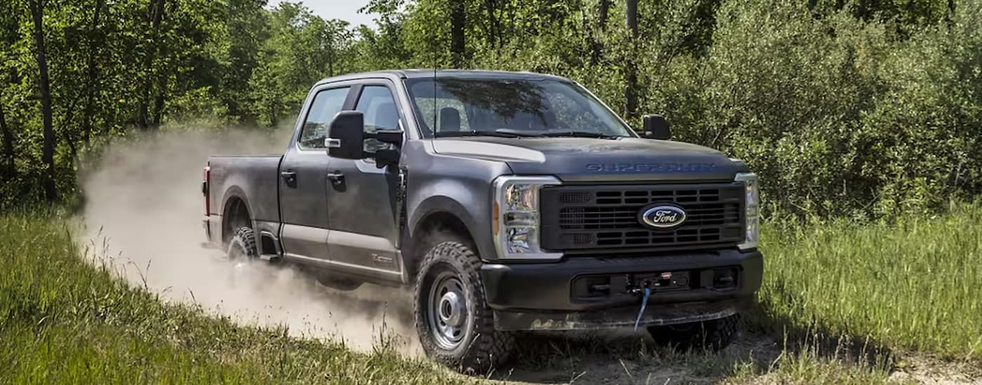 Grey 2025 Ford F-250 Super Duty off-roading on a dusty trail.
