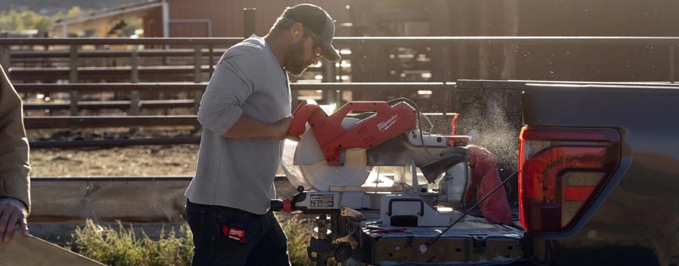 A man using the Pro Power system to run power tools in a black 2024 Ford F-150 for sale near Toledo.