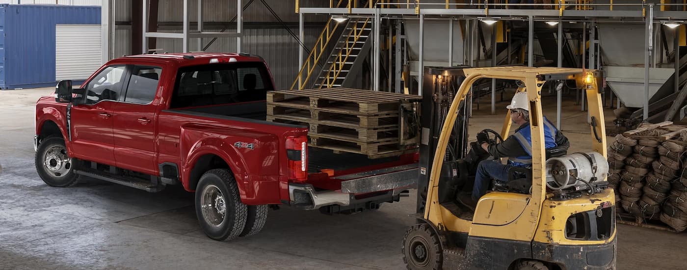 Red 2025 Ford F-350 Dually being loaded with pallets.