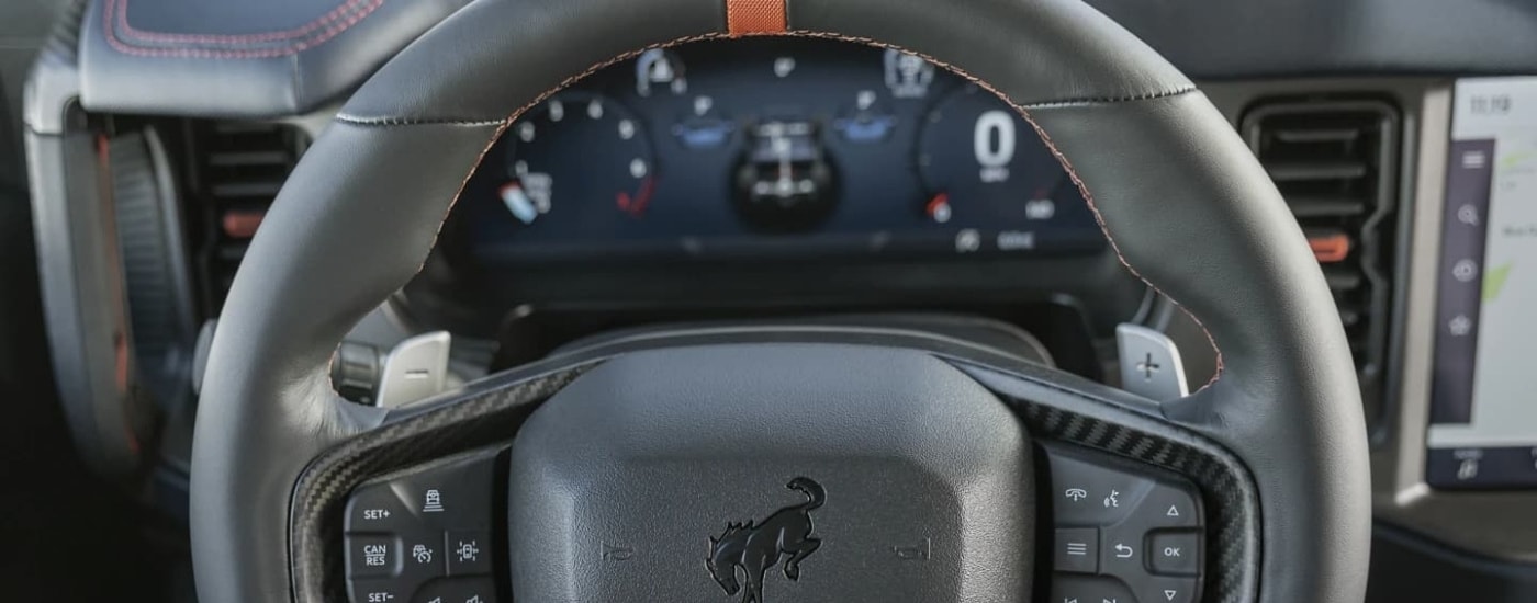 The digital gauge and black steering wheel are shown in a 2023 Ford Bronco Raptor.