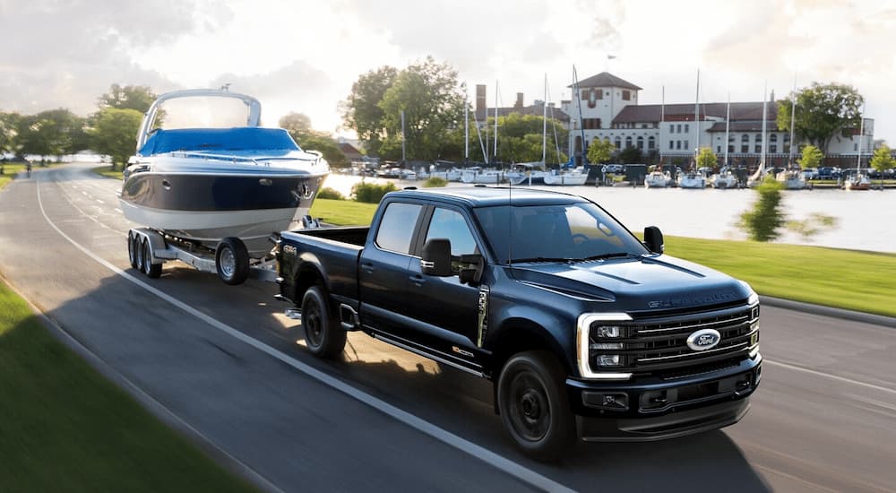 A black 2025 Ford F-350 Platinum is towing a boat near a lake.
