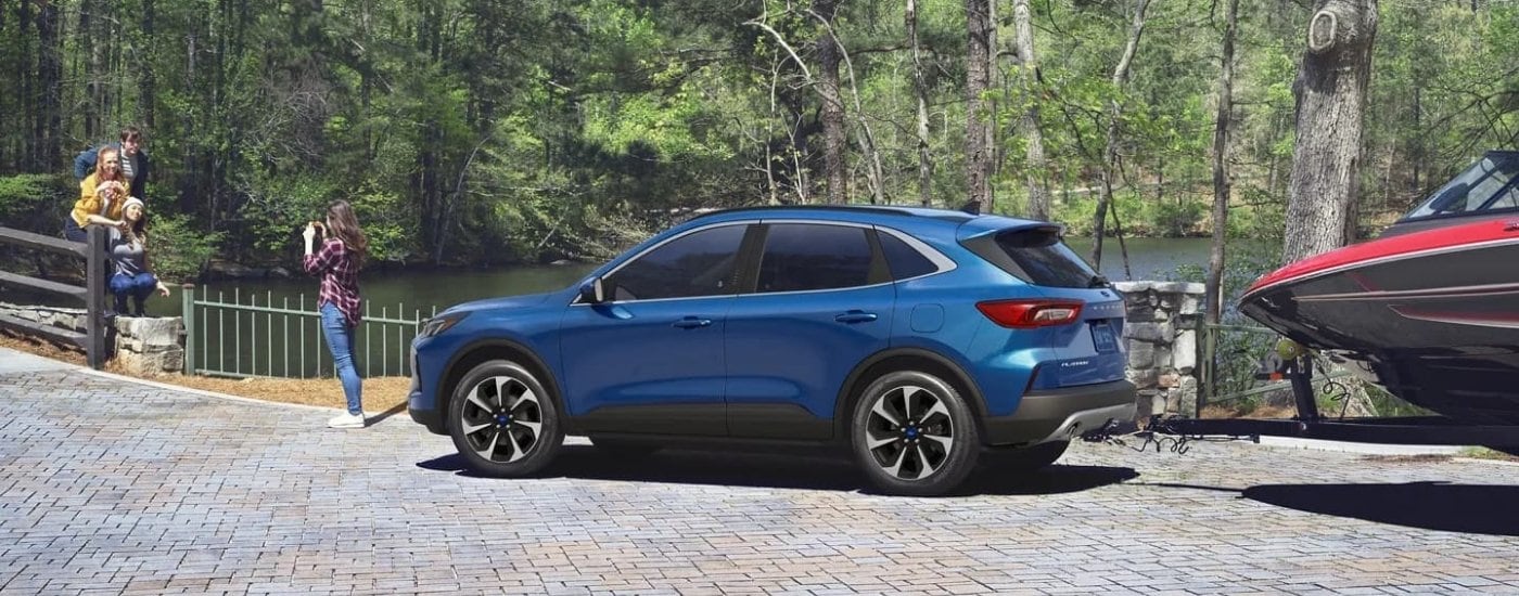 People are shown taking a photo near a blue 2023 Ford Escape Platinum.