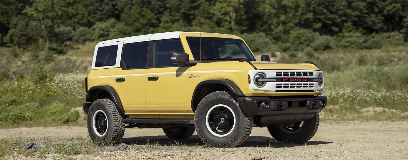 A yellow 2024 Ford Bronco Heritage Limited Edition parked in a field.