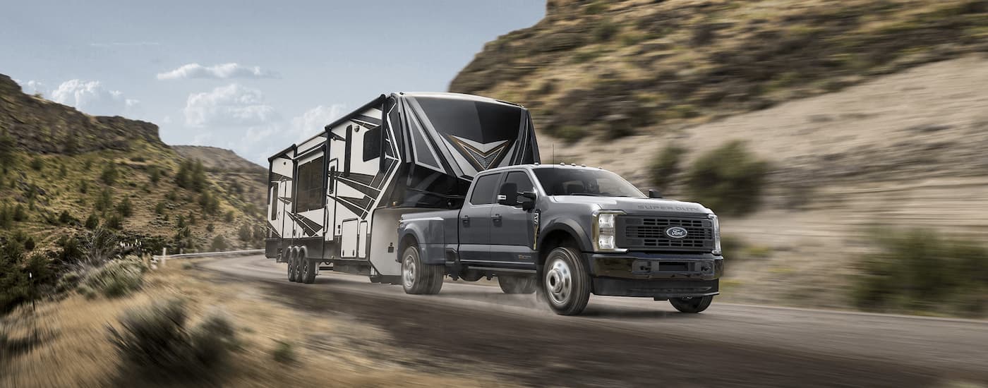 A grey 2025 Ford F-450 XL is towing a camper trailer