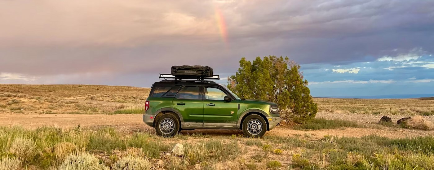 A green 2025 Ford Bronco Sport parked near a rainbow in the sky.