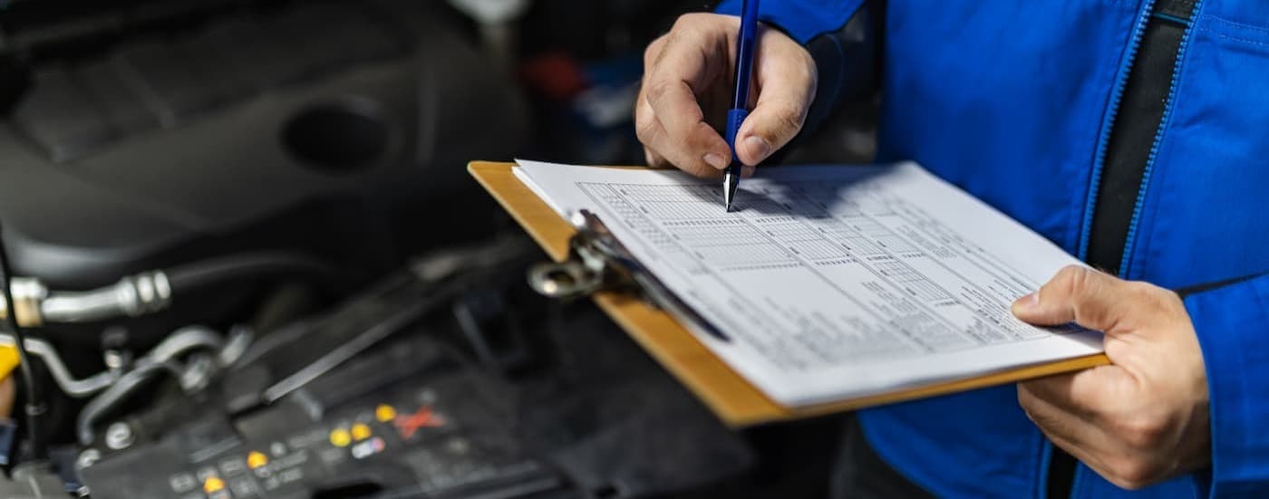 A technician holding a clipboard near an engine.