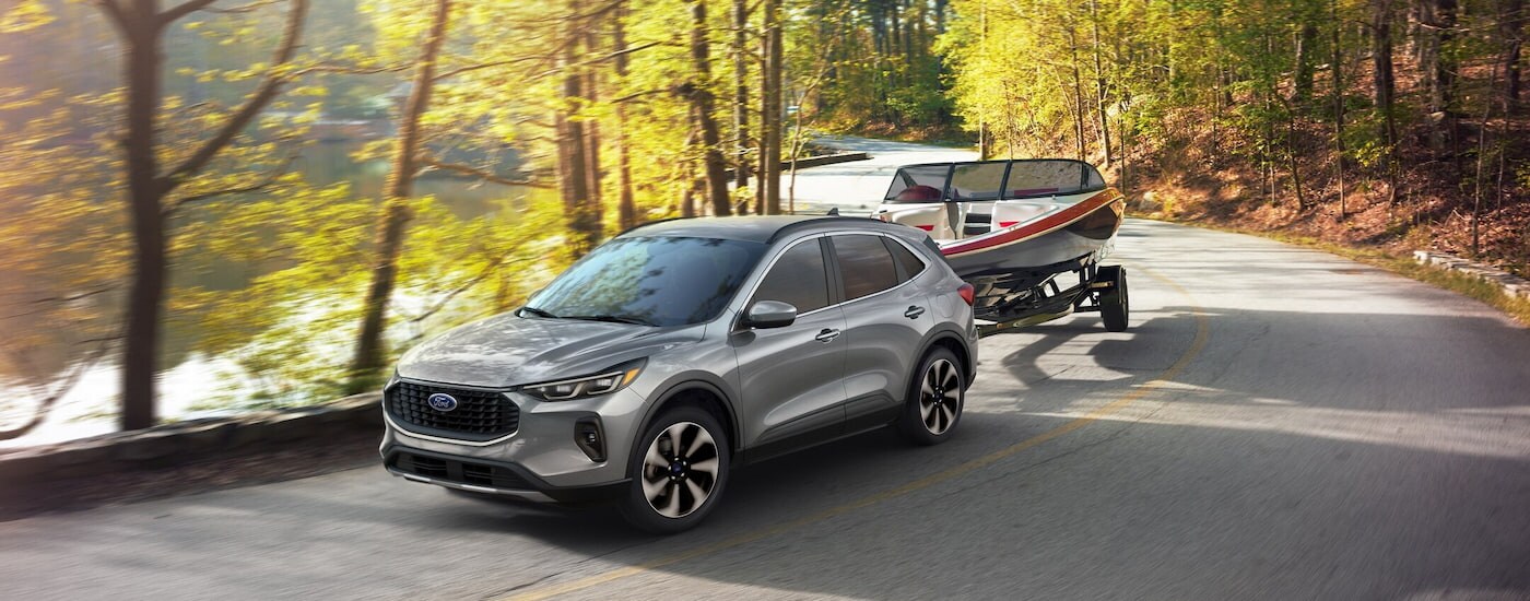 A silver 2024 Ford Escape Platinum towing a boat to a Ford dealer near Forest.