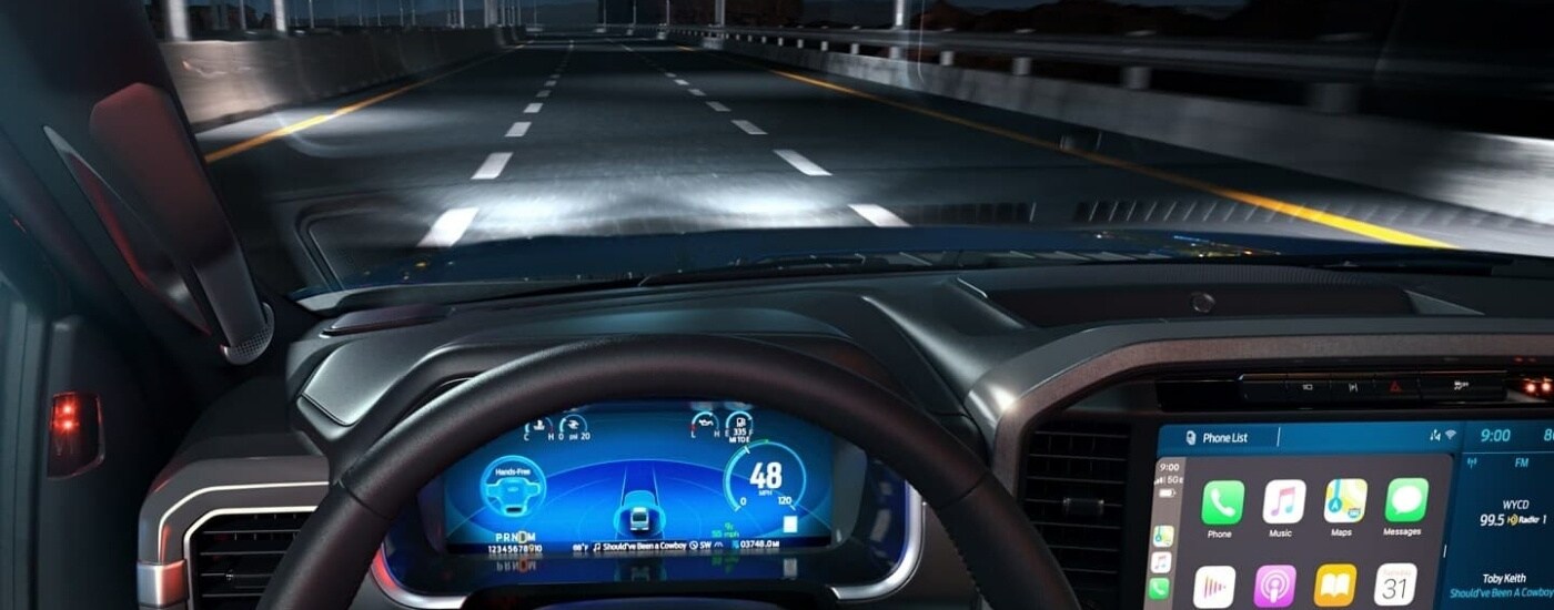 A 2022 Ford F-150 for sale is driving on a bridge at night.