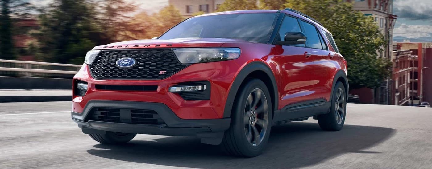 A red 2022 Ford Explorer ST is driving on a city street after viewing a used Ford for sale near Defiance.