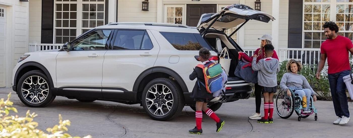 Family with sports gear around a white 2025 Ford Explorer