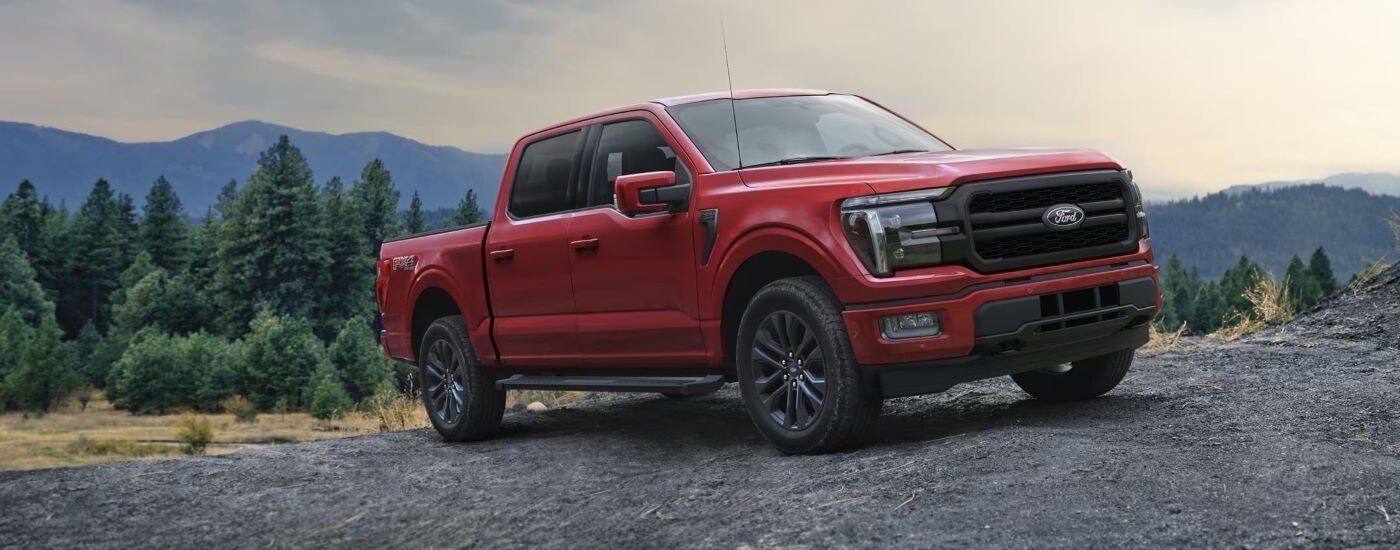 A red 2024 Ford F-150 Lariat parked on grass