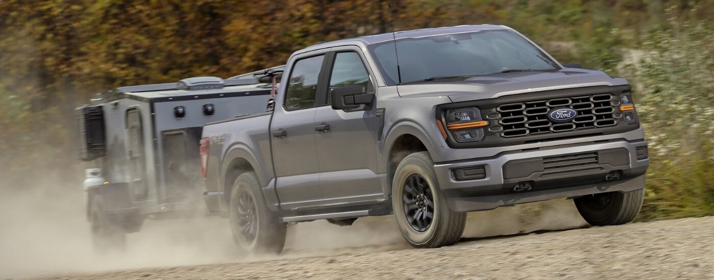 A grey 2025 Ford F-150 for sale near Upper Sandusky is shown towing a trailer off-road.