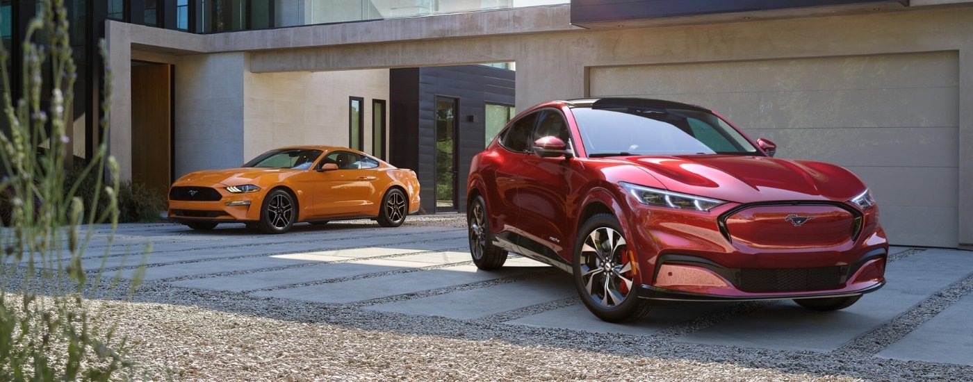 An orange 2021 Ford Mustang parked next to a red 2021 Ford Mustang Mach-E