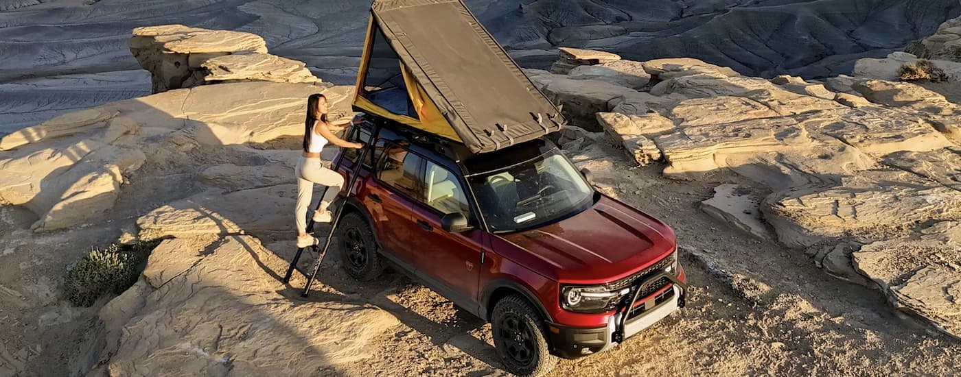 Woman climbing into the rooftop tent on a red 2025 Ford Bronco Sport for sale near Carey