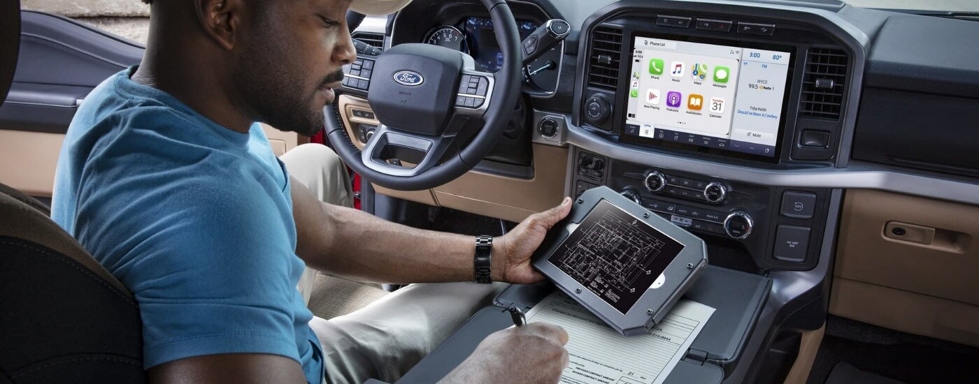 A person is shown reviewing blue prints in a 2023 Ford F-150.
