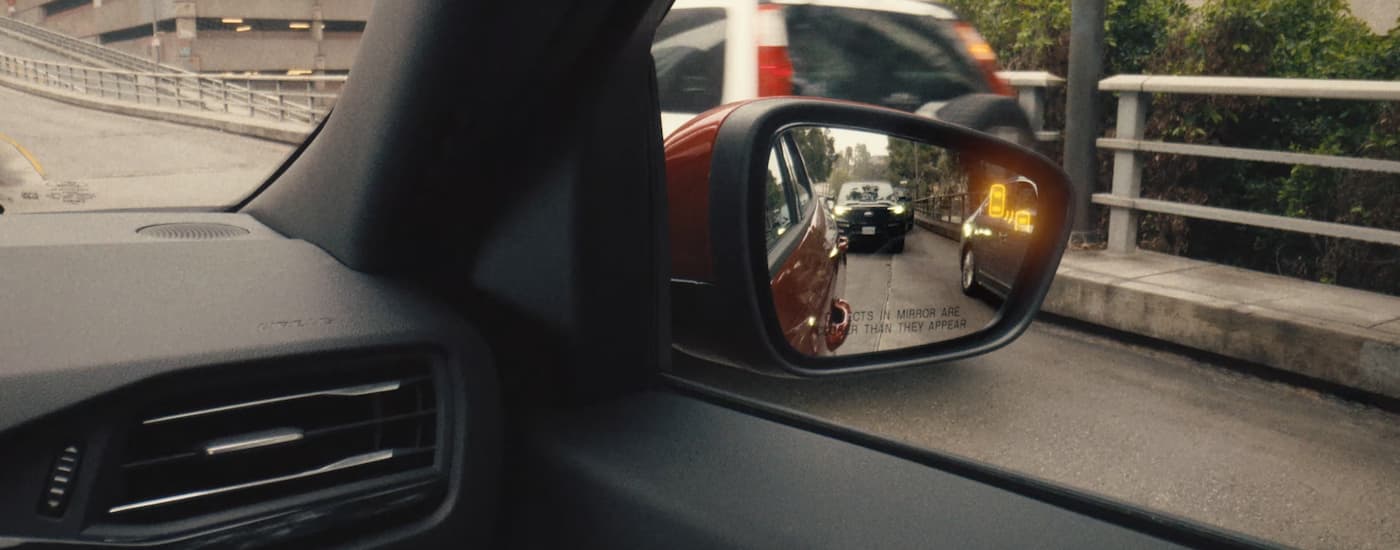 SUV in the side mirror on a red 2025 Ford Escape.