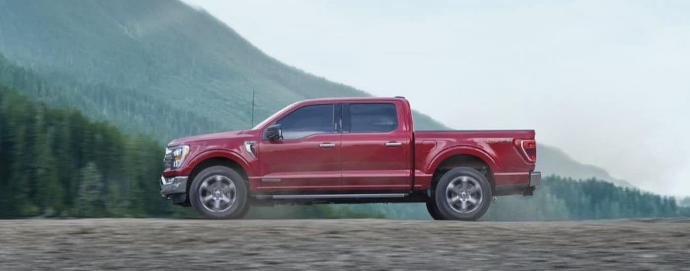 A red 2023 Ford F-150 is shown driving off-road.