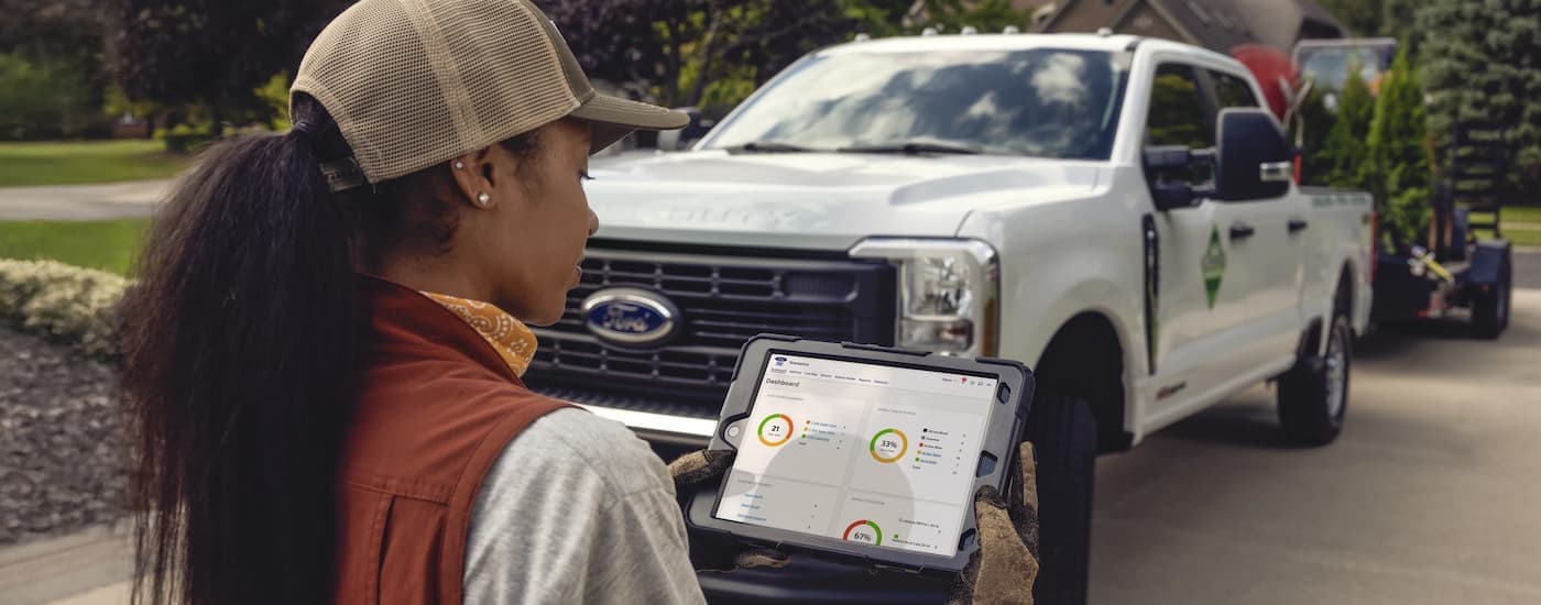 Worker tablet with next to a white 2025 Ford F-250.