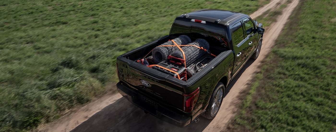 Overhead view of a blue 2024 Ford F-150 Platinum driving through a field with farming materials in the bed.