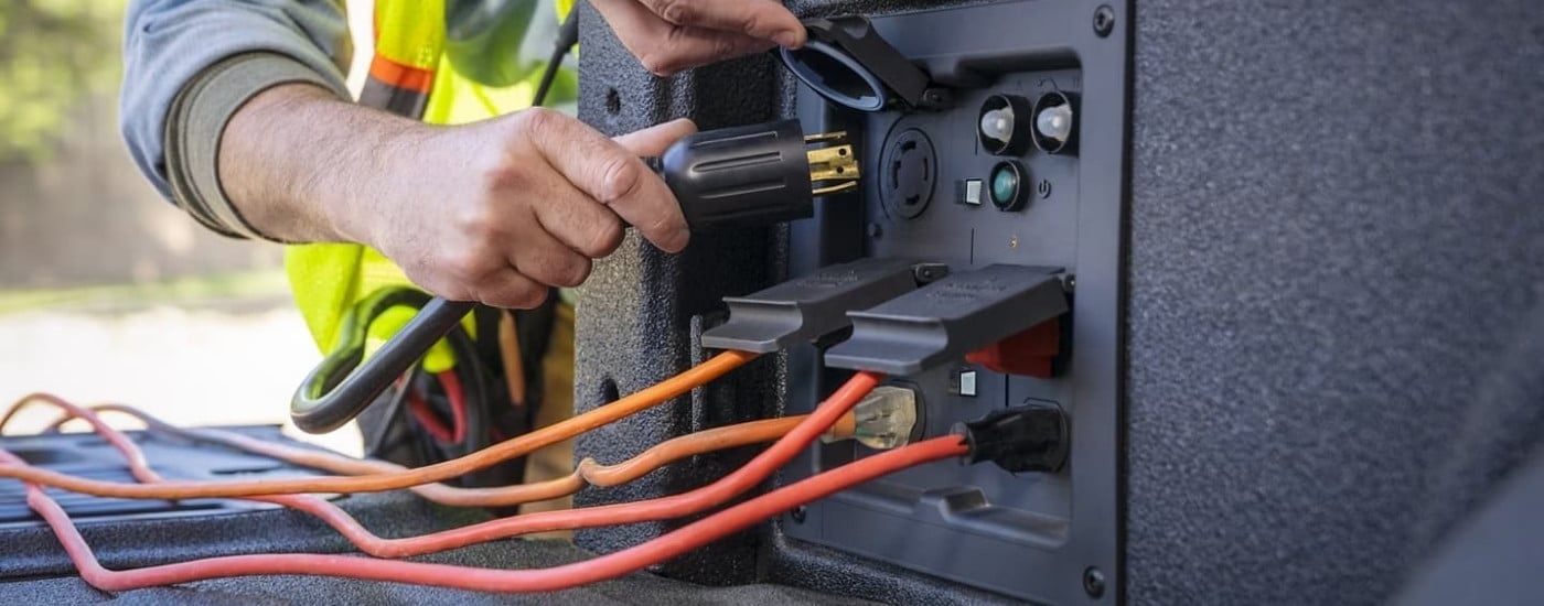 A worker is shown using the bed outlets on a 2022 Ford F-150.