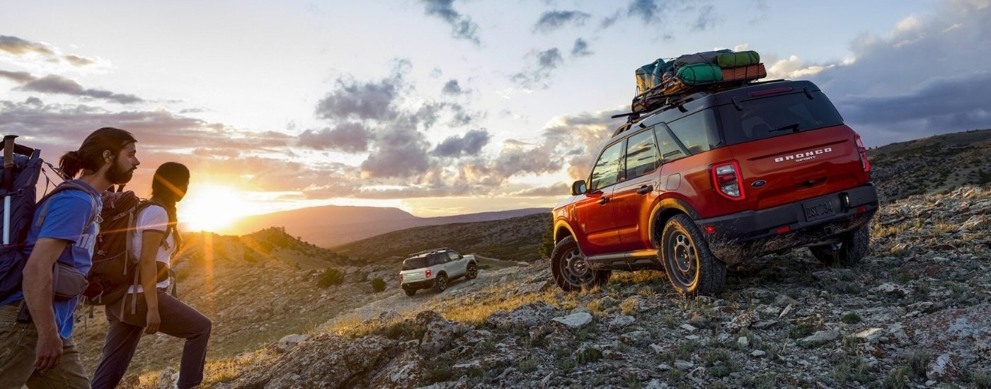 A white and a red 2024 Ford Bronco Sport are shown off-road at sunrise.
